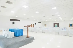 Elegant white banquet hall in Madurai set up for events with a stage and seating arrangements - Heritage Madurai