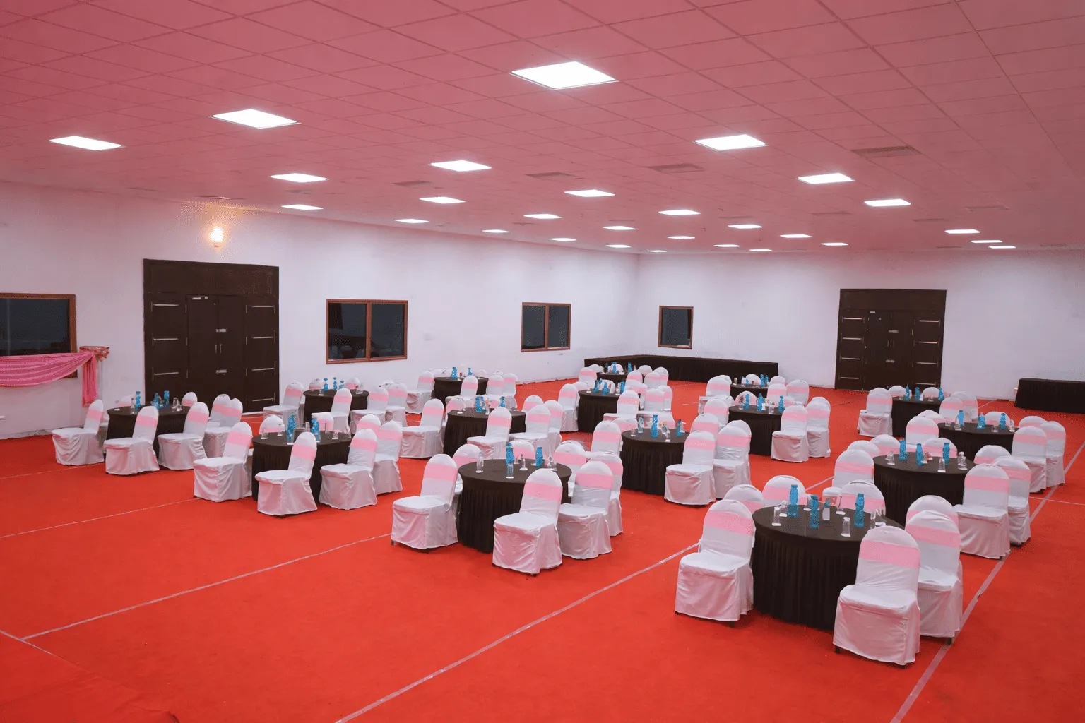 Spacious Chettinadu Hall set up for a corporate event with round table seating, modern lighting, and banquet arrangements in Madurai.